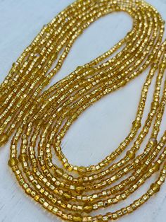 Description One 50 inch tie-on luxury waist bead Created on a durable Ghanian string Shimmery gold seed beads with faceted gold crystals Festive Multi-strand Gold Beaded Jewelry, Festive Multi-strand Jewelry With Gold Beads, Elegant Gold Beaded Necklace With Spacer Beads, Elegant Gold Beaded Necklace With Tiny Beads, Elegant Yellow Jewelry With Tiny Beads, Festive Gold Jewelry With Tiny Beads, Gold Rondelle Bohemian Jewelry, Bohemian Gold Jewelry With Spacer Beads, Adjustable Gold Long Beaded Necklaces