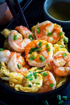 a bowl filled with shrimp and noodles next to chopsticks