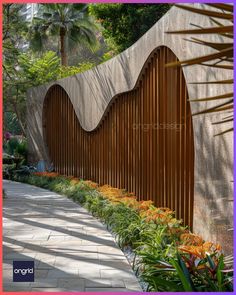 a long wooden fence is next to some plants and flowers in front of a building