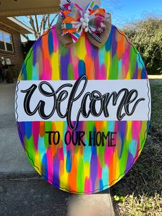 a colorful welcome sign with the words welcome to our home on it and a bow