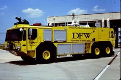 a yellow fire truck parked in front of a building with the words dfw on it