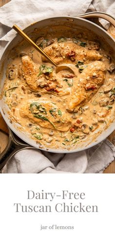 a pan filled with chicken covered in sauce on top of a wooden table next to spoons