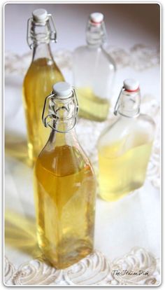 three glass bottles filled with liquid sitting on top of a white doily covered table