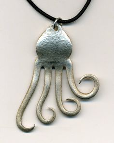 an octopus shaped metal pendant on a black cord