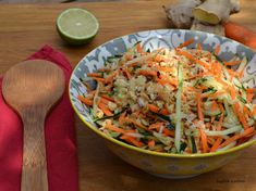 a bowl filled with carrots, celery and other vegetables next to a wooden spoon