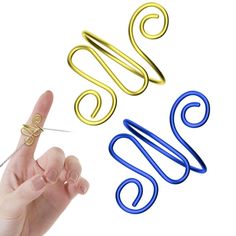 a pair of scissors and some wire on a white surface with one finger pointing at the other