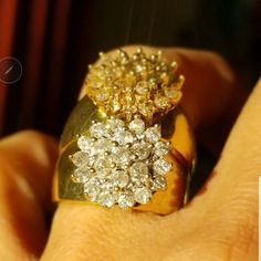 a close up of a person's hand holding a gold and diamond ring