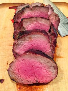 sliced meat sitting on top of a cutting board next to a knife