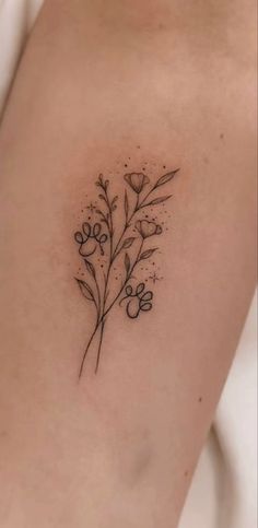 a small flower tattoo on the back of a woman's arm