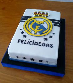 a cake that is sitting on top of a wooden table and has the logo of real madrid