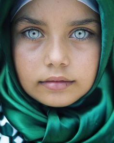 a young woman with blue eyes wearing a green shawl and looking at the camera