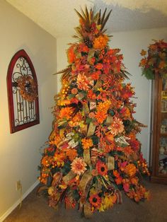 a decorated christmas tree in the corner of a room with orange and yellow flowers on it