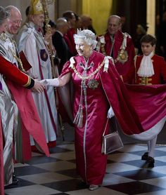 the queen is shaking hands with some men in red and white robes, all dressed in regal garb