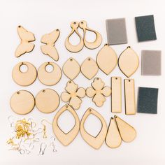 wooden cutouts and other crafting supplies laid out on a white surface, including scissors, pegs, paper clips, earring rings, and more