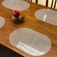 a bowl filled with apples sitting on top of a wooden table covered in white circles