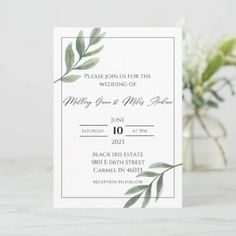 a white wedding card with green leaves on it