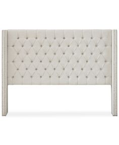 an upholstered headboard with buttons and studding on the top, in white linen