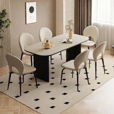 a dining room table with chairs and a potted plant on the rug in front of it