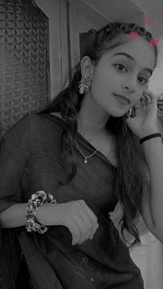 a woman talking on a cell phone while sitting in front of a wall with pink hearts