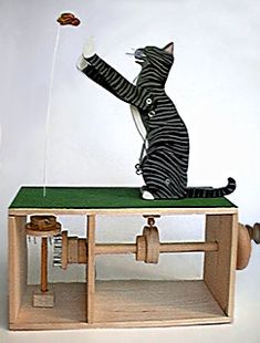 a cat that is sitting on top of a table with a kite in the air