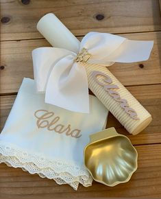 two personalized napkins and a seashell on a wooden table with a ribbon