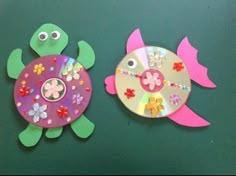 two paper plates are decorated to look like fish and turtle with flowers on their backs