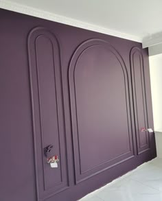 an empty room with purple walls and white floors