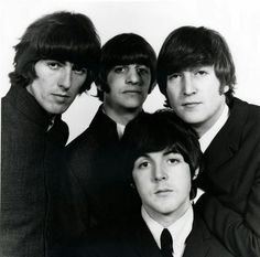 the beatles are posing for a photo in black and white, against a blue background