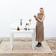 a woman standing next to a white table with flowers on it