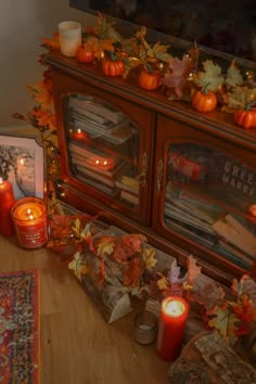 candles are lit in front of an old tv set with fall leaves and pumpkins