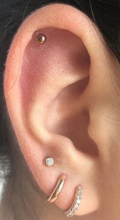 a woman's ear with three different piercings