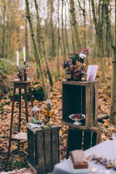 an outdoor picnic setting in the woods with food and drinks on small tables, surrounded by trees