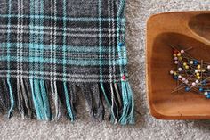 a wooden bowl sitting on top of a carpet next to a plaid blanket and beads