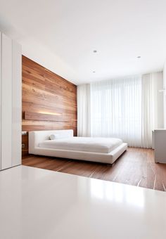 a white bed sitting in the middle of a bedroom next to a wall mounted flat screen tv