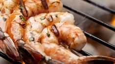 shrimp being cooked on the grill with tongs