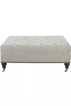 an upholstered bench with wooden legs and buttons on the bottom, in white fabric