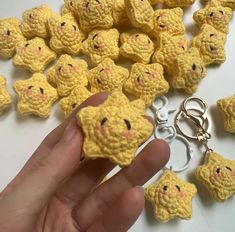 a hand holding a tiny yellow crocheted animal keychain with other small stuffed animals around it