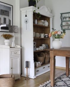 a wooden table sitting next to a white cabinet