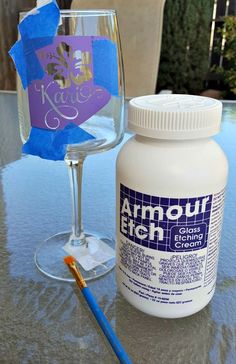 a bottle of paint next to a wine glass with a blue ribbon on the table