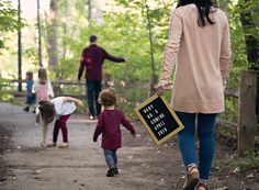 a woman and two children walking down a path in the woods with a sign that says not all those little kids are allowed