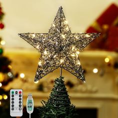 a christmas tree with a star on top and remote control in front of the fireplace