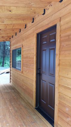 a wooden porch with two brown doors and wood flooring on the side of it