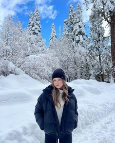 a woman standing in the snow with her hands on her hips and looking at the camera