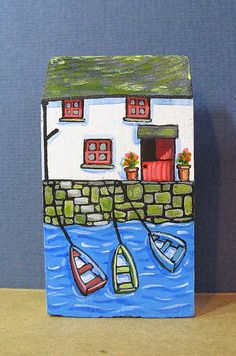 a painting of boats floating in the water near a house with red doors and windows