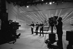 black and white photograph of three men in front of a camera set up for a recording