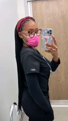 a pregnant woman wearing a pink face mask taking a selfie in the mirror with her cell phone