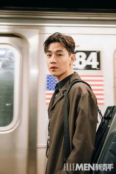 a young man standing in front of a subway train