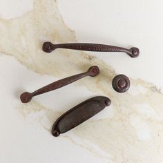 three wooden handles on a marble counter top with rusted metal knobs in the middle