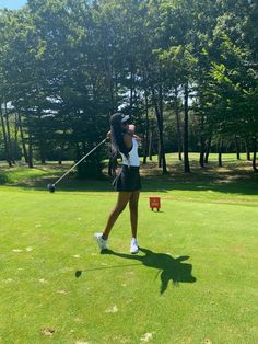 a woman is swinging her golf club on the green