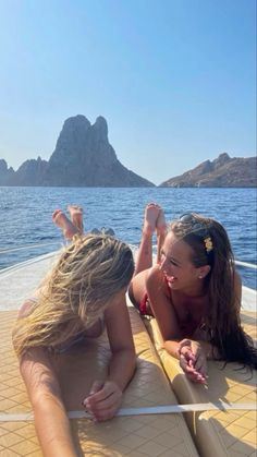 two women laying on the back of a boat